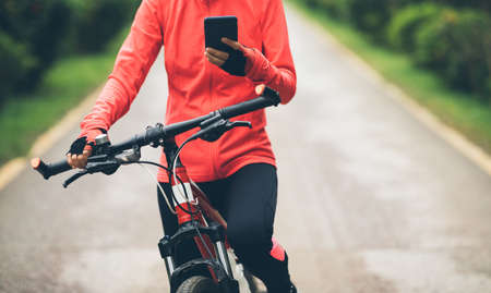 Cyclist use smartphone when riding mountain bike on forest trailの写真素材