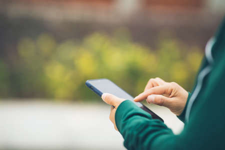 Asian woman using smartphone outdoorsの写真素材