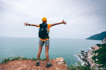 Successful hiker outstretched arms at seaside mountain top cliff edgeの写真素材