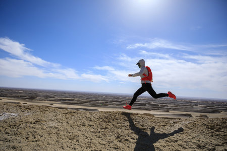 Asian woman trail runner cross country running on sand desert dunes