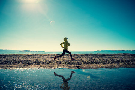 Woman trail runner cross country running in winter lakeside