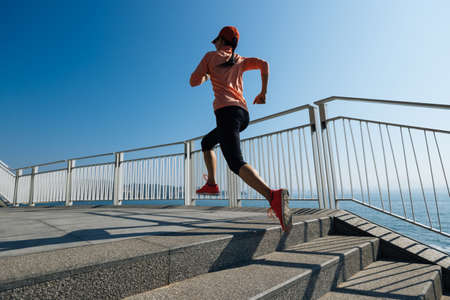Healthy lifestyle fitness sports woman runner running up stairs on seaside trailの写真素材