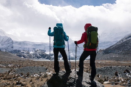 Two women hikers hiking in winter high altitude mountains