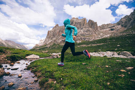 Woman trail runner running in wild mountainsの写真素材