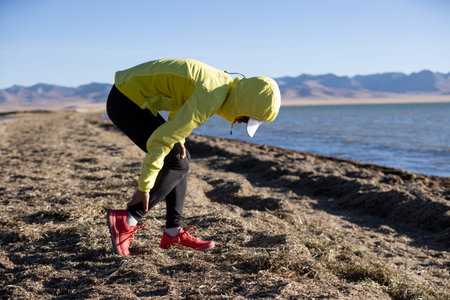Woman runner with sports injured leg running at sunset sandy beach