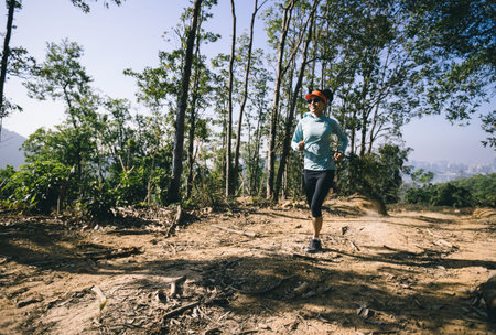 Young woman trail runner running in sunrise tropical forest mountain topの写真素材