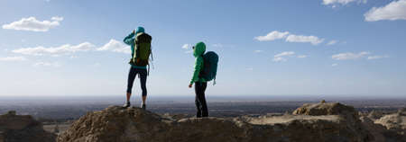 Two women backpackers hiking on sand desert dunesの写真素材