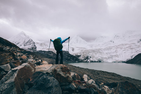 Cheering woman backpacker hiking in winter high altitude mountains