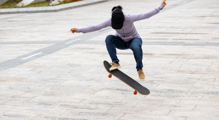 Asian woman skateboarder skateboarding in modern city