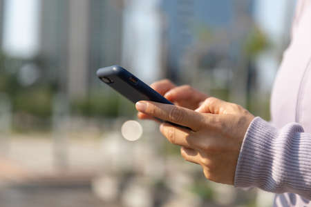 Asian woman using smartphone outdoorsの写真素材