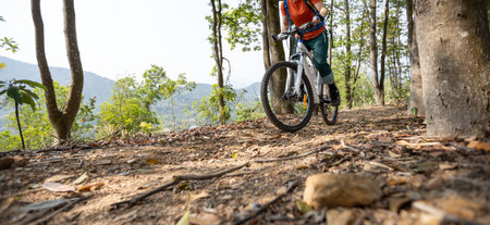 Woman cyclist cycling on spring mountain top forest trailの写真素材