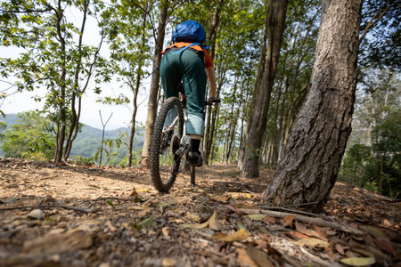 Woman cyclist cycling on spring mountain top forest trail