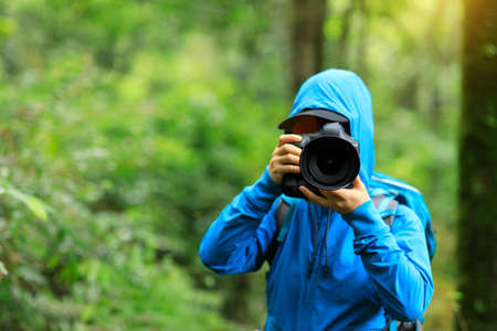 Woman photographer taking photo  in spring forestの写真素材