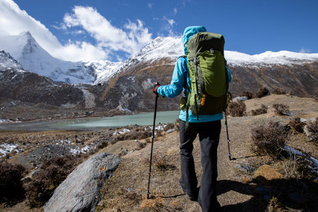 Woman backpacker hiking in winter high altitude mountains