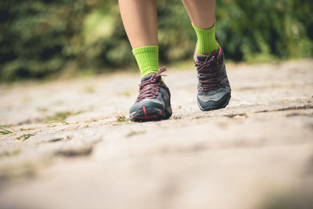 Young fitness woman hiker legs walking at forest trail