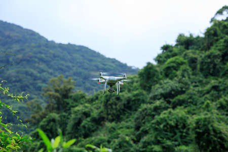 White drone with camera flying in spring mountainsの写真素材
