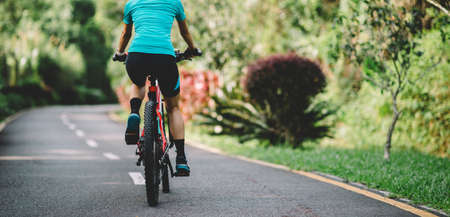 Woman cycling on tropical park trail in summerの写真素材