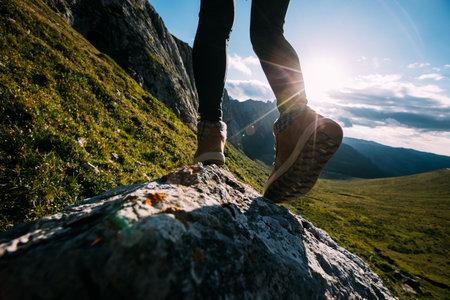 Successful woman hiker legs hiking on sunset alpine mountain peakの写真素材