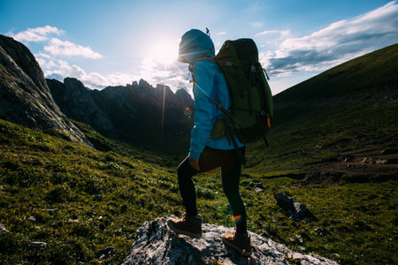 Successful woman backpacker hiking on sunset alpine mountain topの写真素材