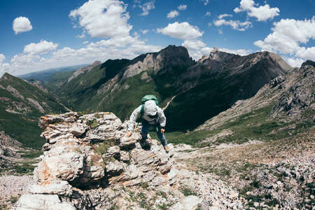 Successful woman backpacker hiking on alpine mountain topの写真素材