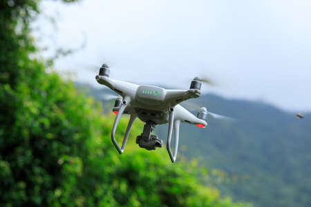 White drone with camera flying in summer mountainsの写真素材