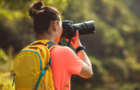 Woman photographer taking pictures in autumn forestの写真素材