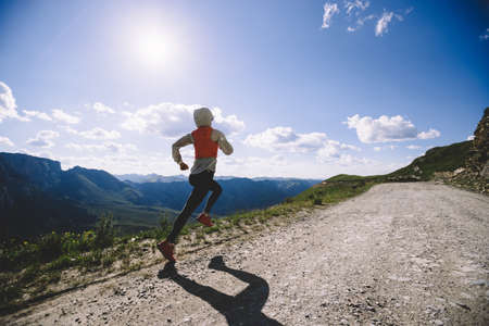 Woman trail runner running on mountain topの写真素材
