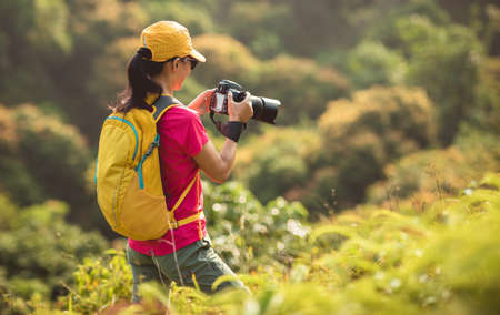 Woman photographer taking pictures in autumn forestの写真素材