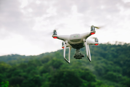 White drone with camera flying in summer forest