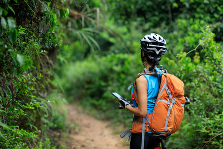 Woman cyclist use smartphone when riding mountain bike on forest trailの写真素材