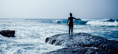 Woman surfer with surfboard going to surf on seasideの写真素材