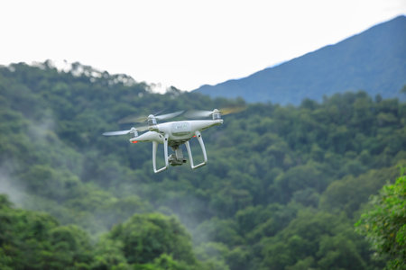White drone with camera flying in summer forest