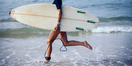 Surfer woman running with surfboard on the beach