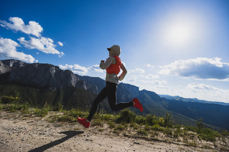 Young woman ultramarathon runner running at mountain topの写真素材
