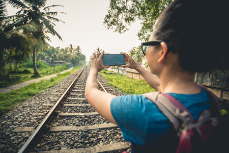 Woman tourist using mobile phone taking photo of rail way