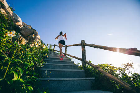 Young fitness woman running upstairs on mountain stairsの写真素材