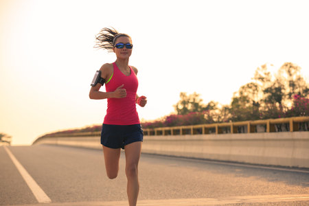 Young fitness woman runner running on road