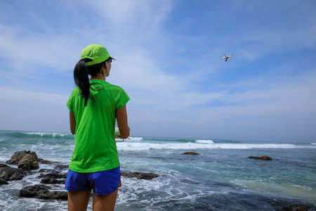 Woman photographer taking selfie wiht a drone on seasideの写真素材