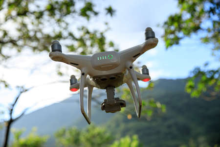 White drone with camera flying in summer forestの写真素材