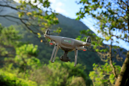 White drone with camera flying in summer forestの写真素材