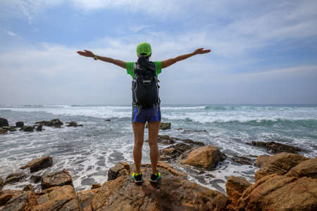 Woman enjoying nature with her opened arms on seaside cliff edgeの写真素材
