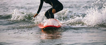 Surfer woman practice surfing in the white waterの写真素材