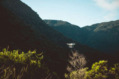 White drone with camera flying in summer mountainsの写真素材