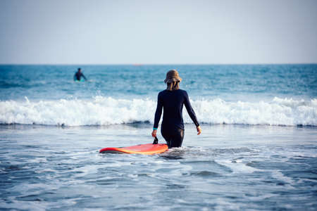 Surfer woman practice surfing in the white waterの写真素材