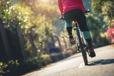 Woman riding a bike on tropical park trail in springの写真素材