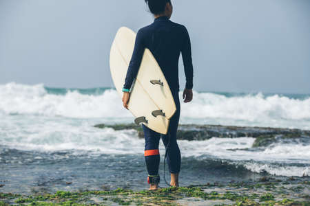 Woman surfer with surfboard going to surf the big wavesの写真素材