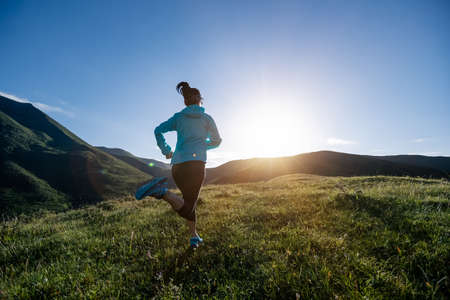 Young woman runner running at mountain topの写真素材