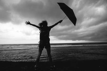 Woman with umbrealla stand in the storm at seasideの写真素材