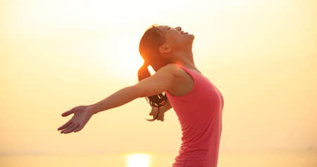Woman open arms under the sunrise at seasideの写真素材