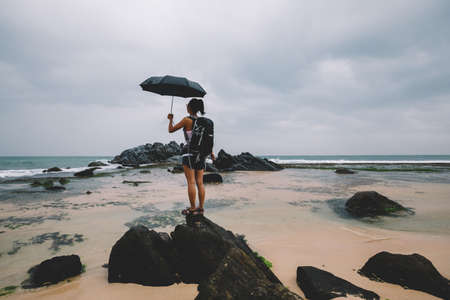 Woman with umbrealla stand in the storm at seasideの写真素材
